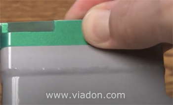 Green poly tape being pressed down to activate pressure sensitive adhesive