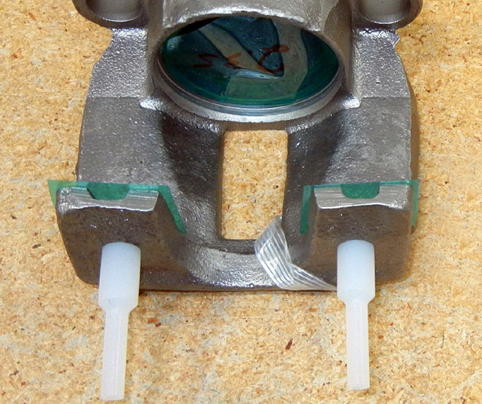 Masking tape and plugs on brake caliper for powder coating